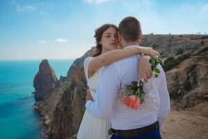 Beautiful smiling young bride and groom walking on the beach, kissing and having fun, wedding ceremony near the rocks and sea. Wedding ceremony on coast of Cyprus