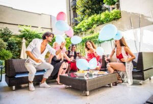 Multiethnic group of friends making party in a lounge bar - Cheerful young adults having fun and celebrating in a backyard garden with swimming pool