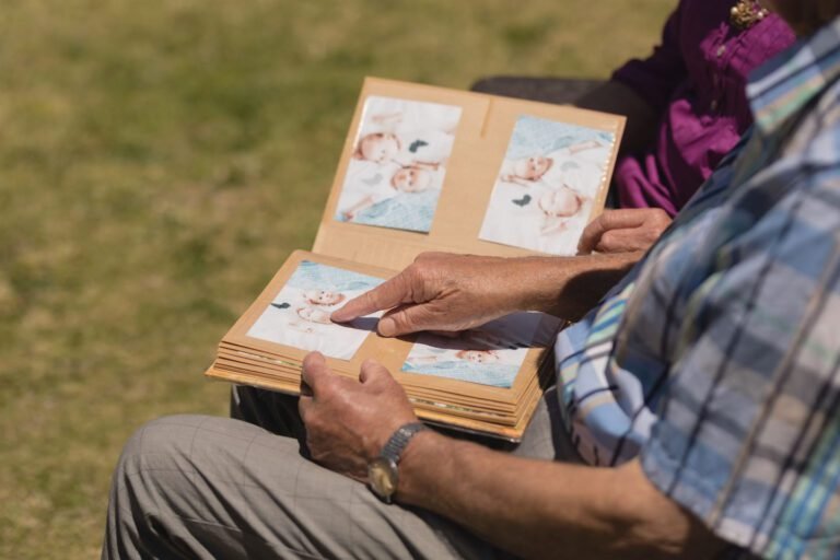 Mid section of senior couple looking at photo album and the man showing a photo in the park