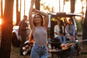 Pretty woman is standing and enjoying nature. Group of friends are having fun together in the forest.