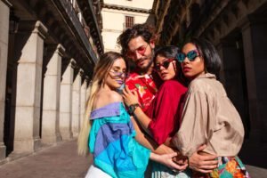 Handsome young man hugging with three women while wearing trendy clothes and standing on street on sunny day
